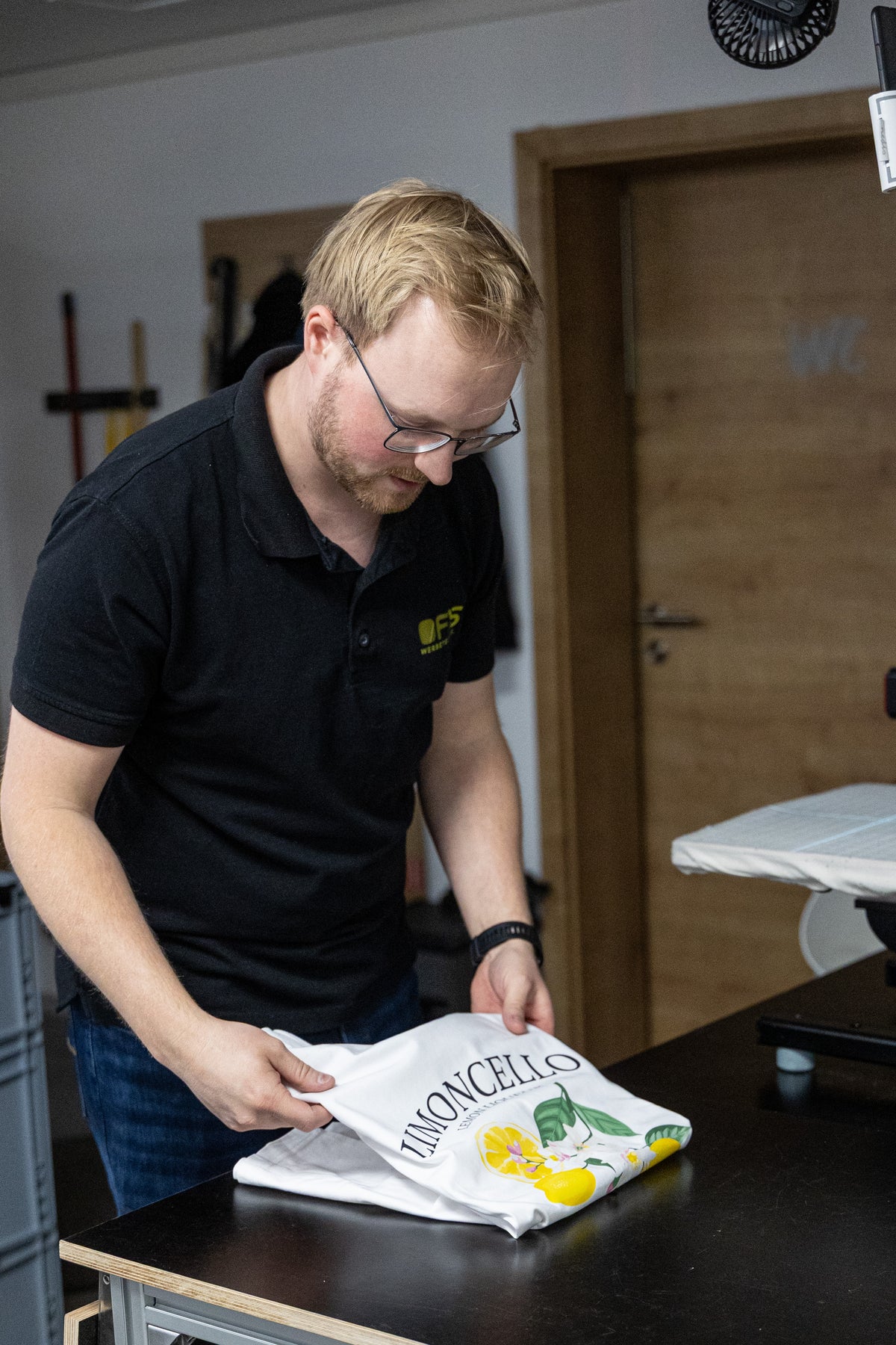 Marco faltet ein bedrucktes Kundenshirt mit Limoncello-Motiv