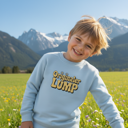 Lachender Junge auf einer Sommerwiese vor Bergkulisse trägt ein hellblaues Kinder-Sweatshirt mit dem gelben Retro-Schriftzug "Originaler LUMP" und Gänseblümchen