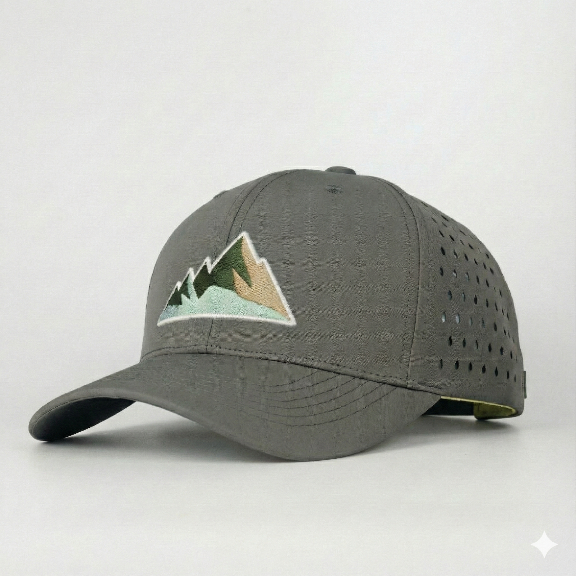 Nahaufnahme einer grauen Outdoor-Cap mit aufgesticktem Berg-Motiv und perforierten Seitenteilen für Belüftung.